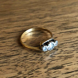 Vintage 3 Stone Diamond Cross Over Engagement Ring with Wood Background