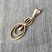 A Petite Art Deco 9ct Gold Garnet Circular Drop Pendant lying flat