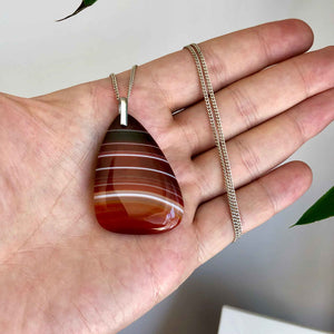Vintage 925 Silver Polished Red Banded Agate Pendant and Chain in Hand Grey Background