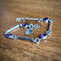 Dainty Cabochon Amethyst Silver Bracelet with Silver Shell Charm on Desk