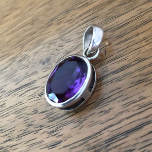 Large Vintage Synthetic Oval Amethyst Pendant lying on Wooden Table top