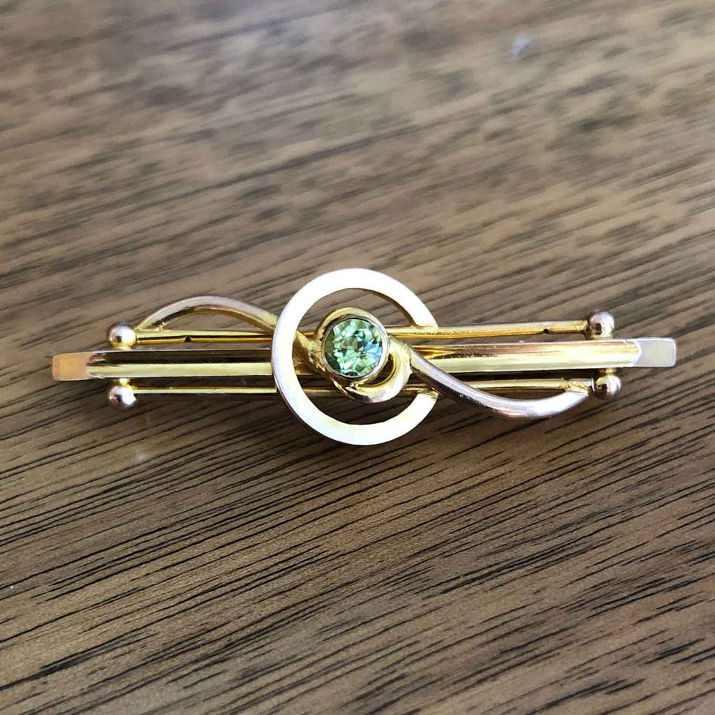 Vintage Art Deco 9k Gold Peridot Bar Brooch Wooden background - Jewellery Hund Antique Jewellery